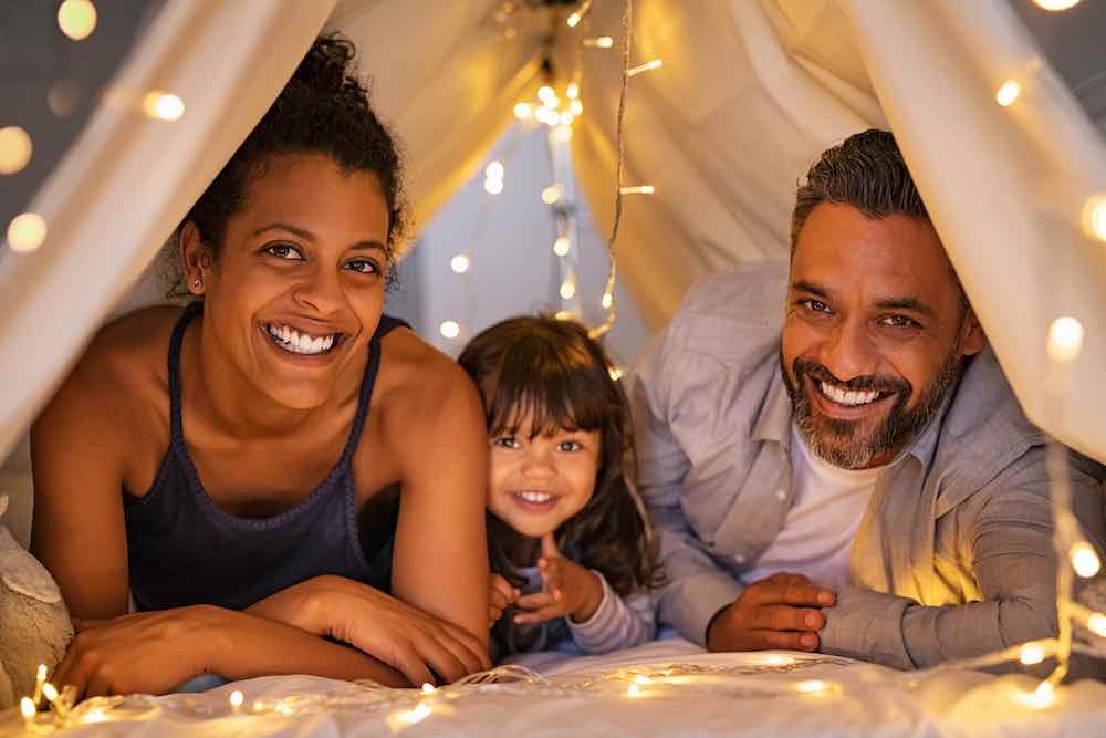 happy parents with daughter have fun in cozy tent